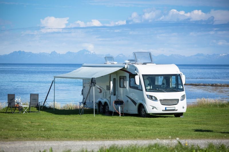 Grote camper met luifel en twee stoelen