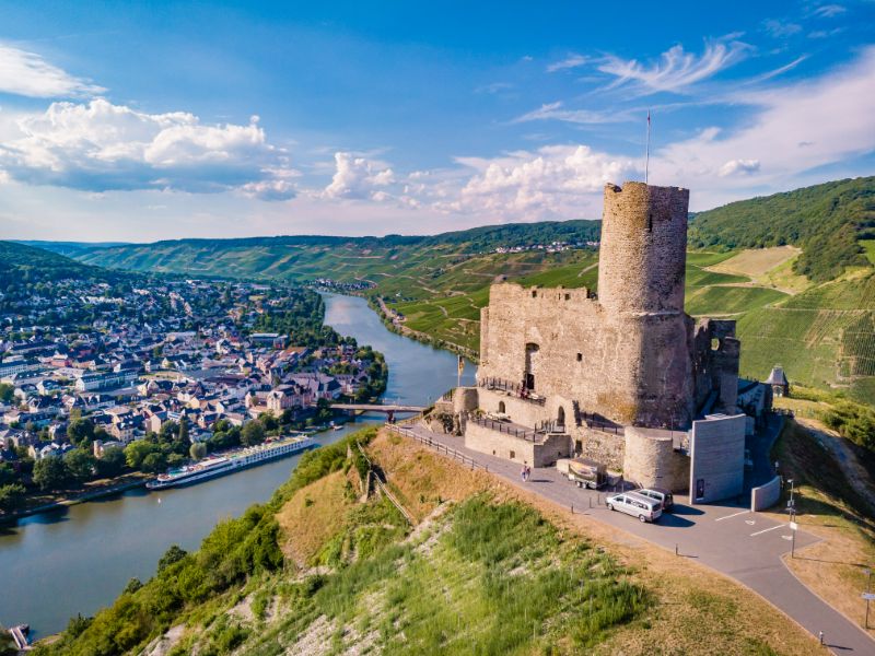 Burg Landshut torent boven de Moezel en de dubbelstad Bernkastel-Kues uit. Op de achtergrond verheffen zich heuvels.