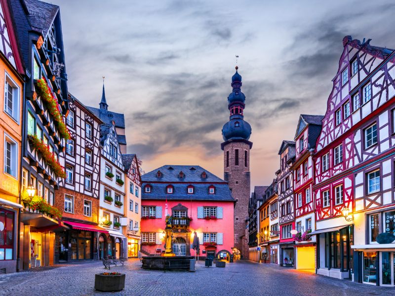 Vakantie aan de Moezel in de mooie vakwerkhuizen van Cochem! Verlichte huizen met kerktoren op de achtergrond.