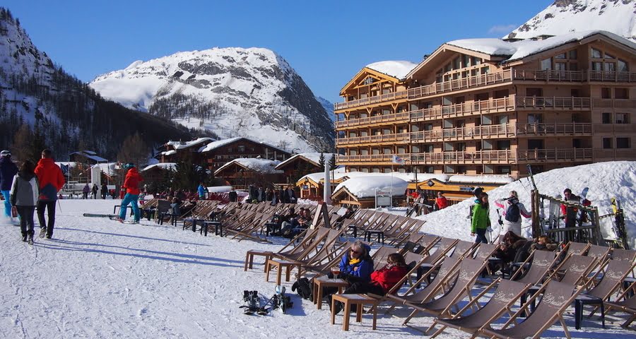 mensen ontspannen in ligstoelen buiten een ski bar