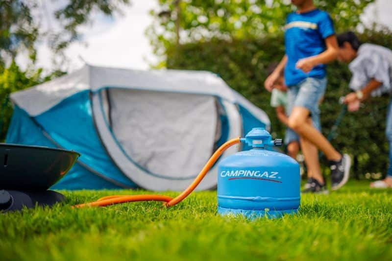 Campingaz aan een oranje slang in het gras