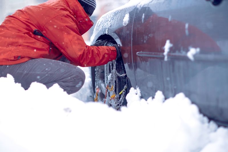 Man brengt sneeuwkettingen aan op autoband