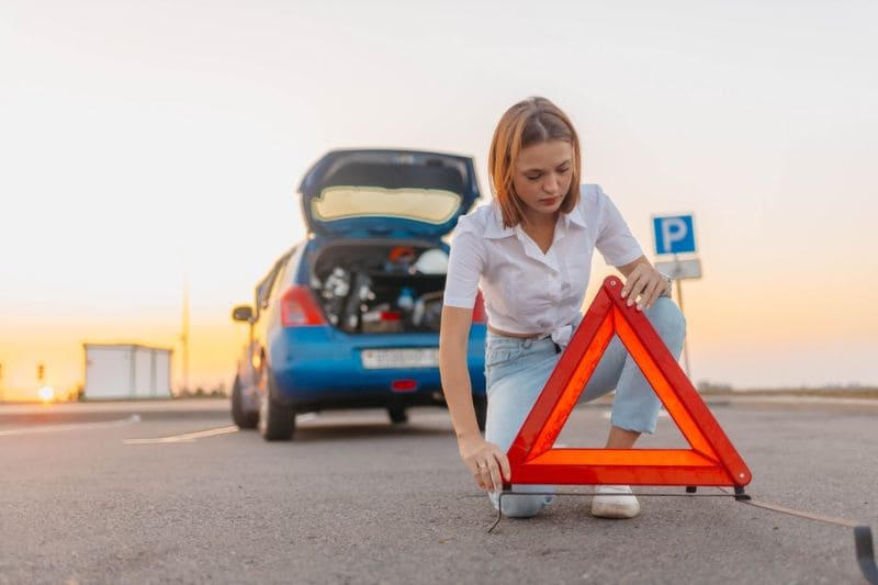 Vrouw plaatst gevarendriehoek op de weg