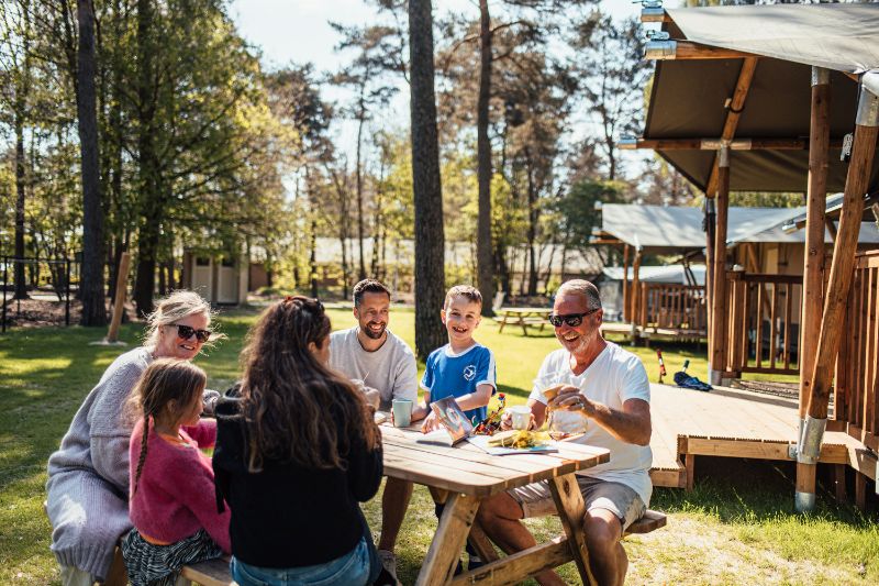 Familie gezellig aan picknicktafel voor safaritent