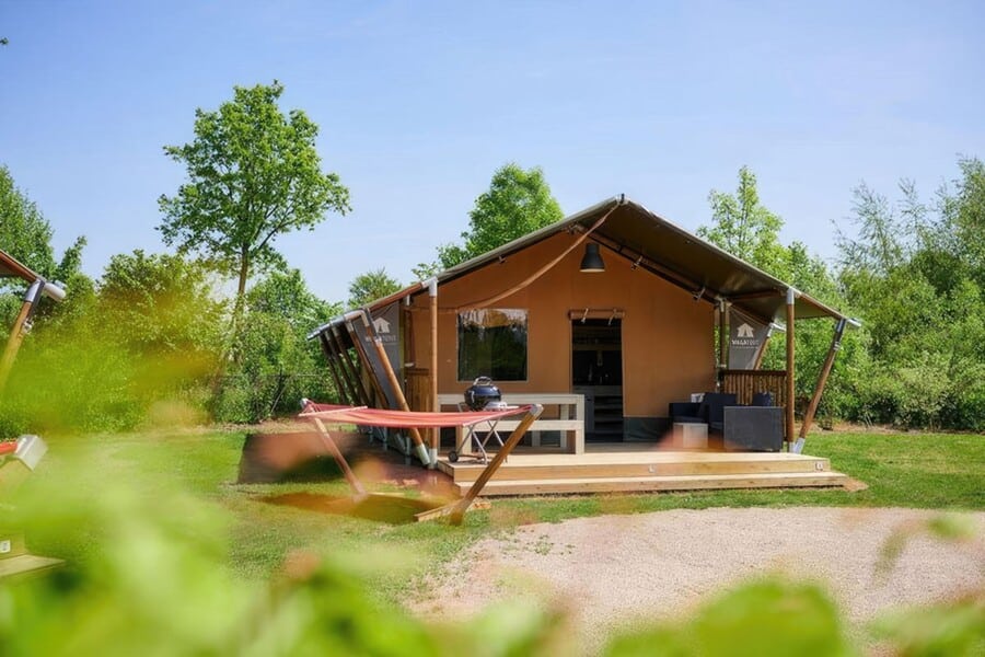 een luxe tent in de zon, op een groen veldje