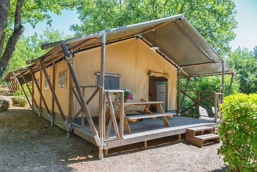 een grote, luxe tent onder de schaduw van de bomen