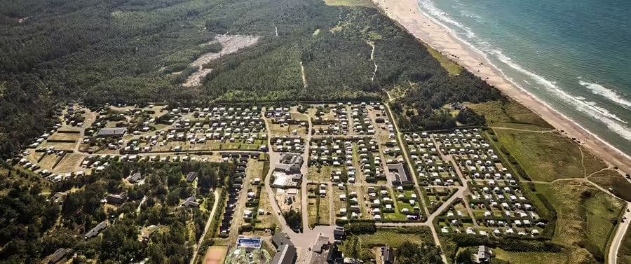 luchtfoto van de camping tussen de bossen en aan zee