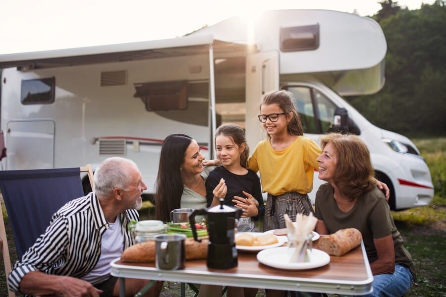 vrolijke familie met broodjes aan een campingtafeltje