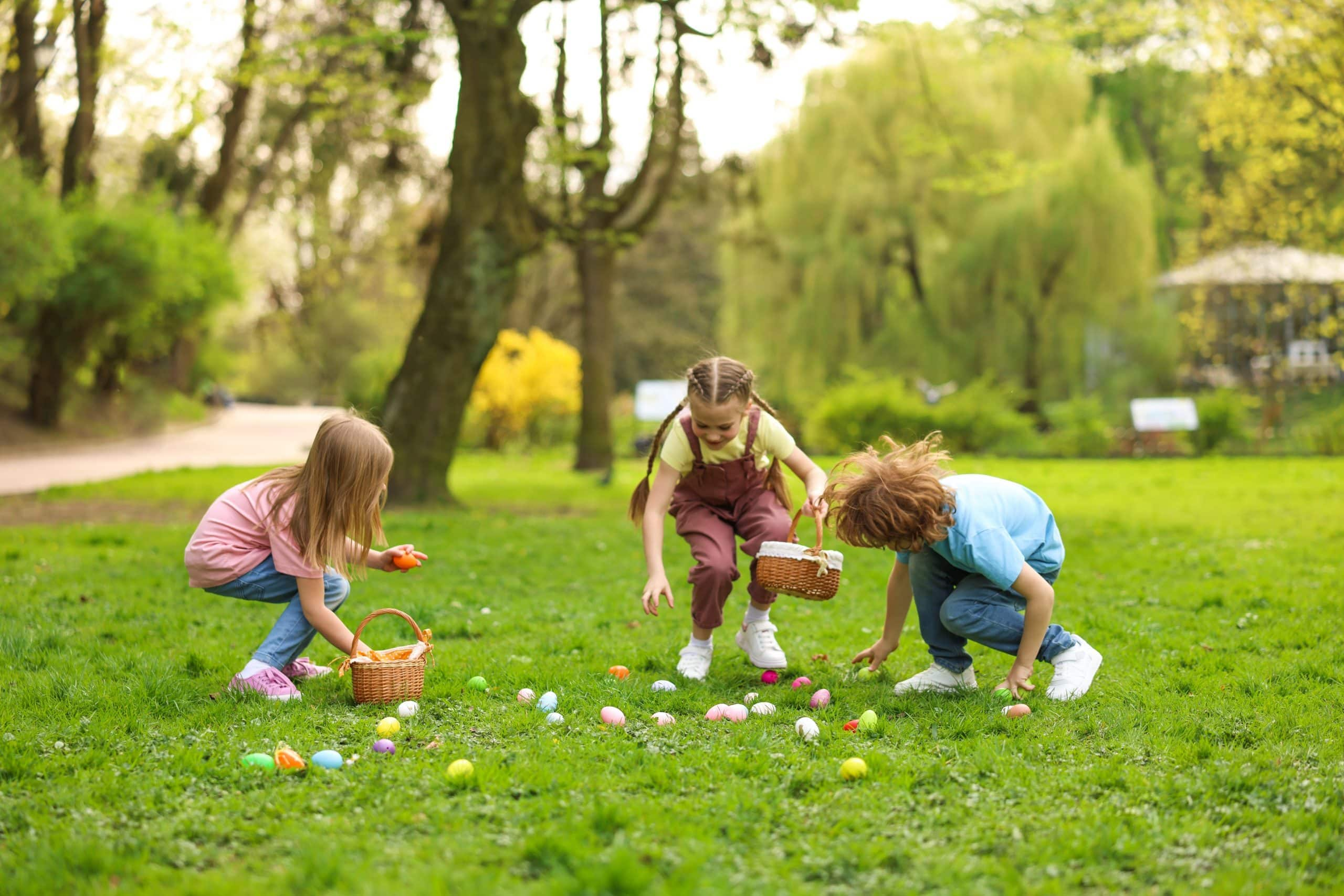 Kinderen zoeken gekleurde paaseieren in het gras